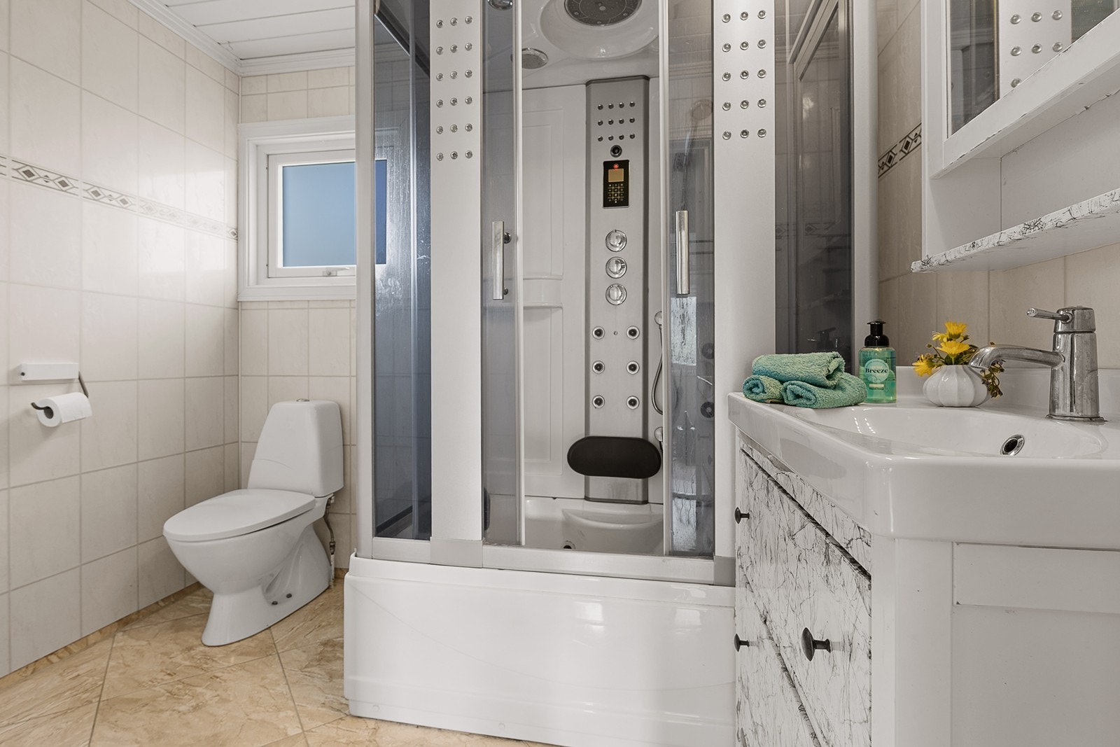 Badet inneholder wc, dusjkabinett m/badekar og servant med skap- og skuffeinnredning. Galleribilde