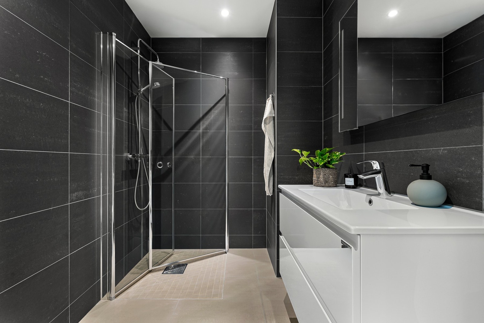 Flislagt bad med dusjhjørne, servant og god belysning. Galleribilde