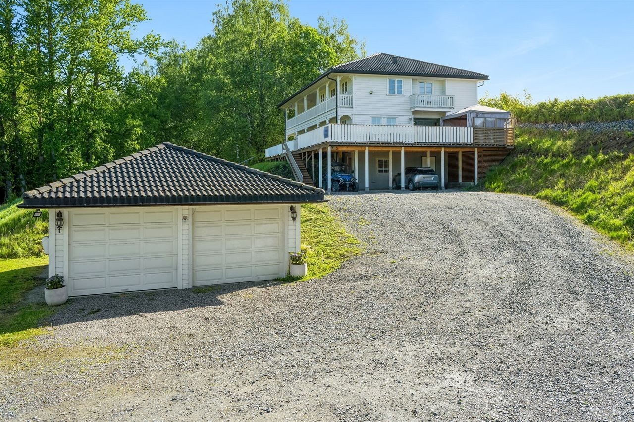 Stort gruset gårdsrom med dobbelgarasje og rikelig med parkeringsmuligheter. Galleribilde