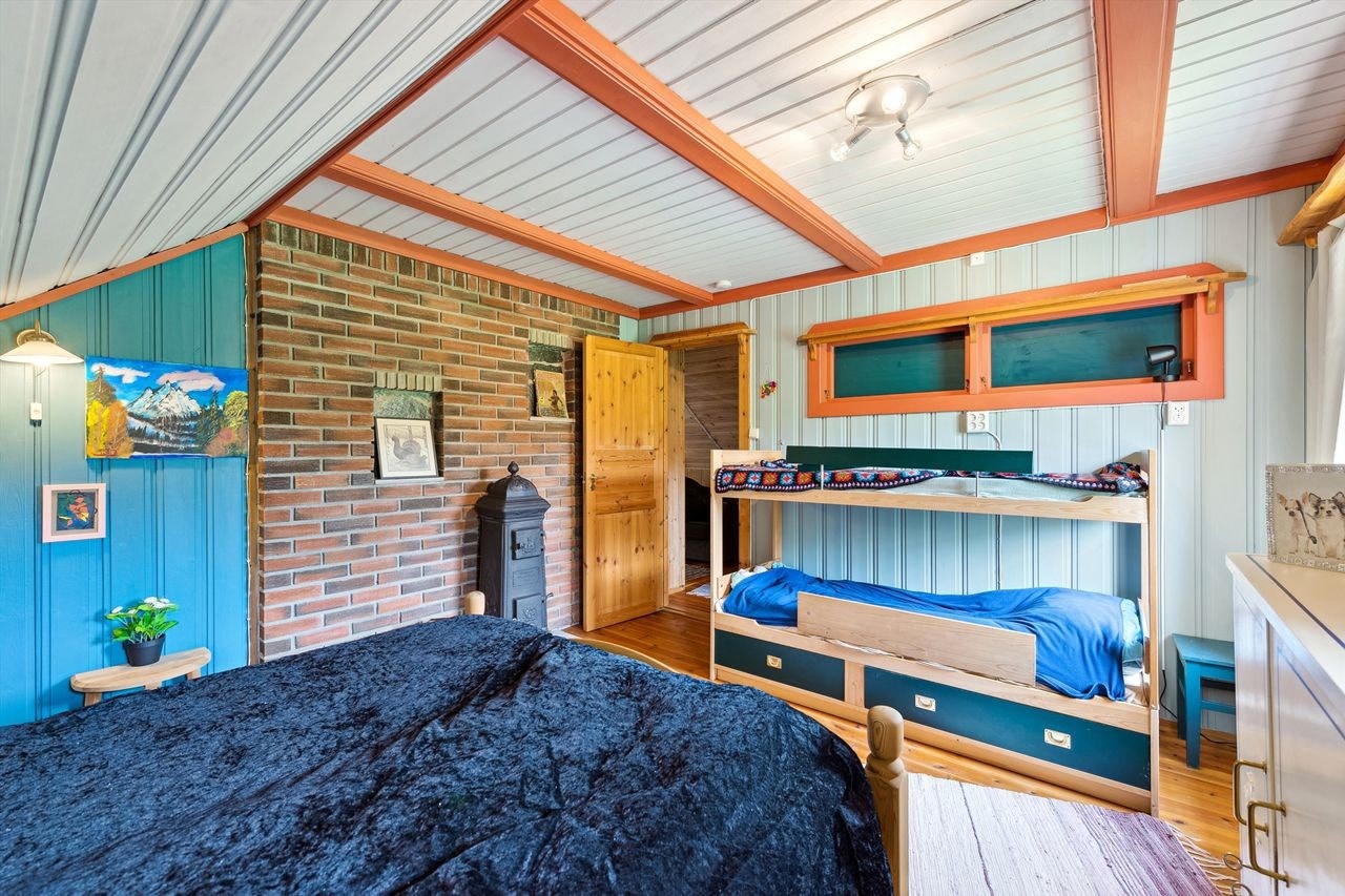 Hovedsoverom med synlig murvegg, vedovn og smarte oppbevaringsløsninger. Galleribilde