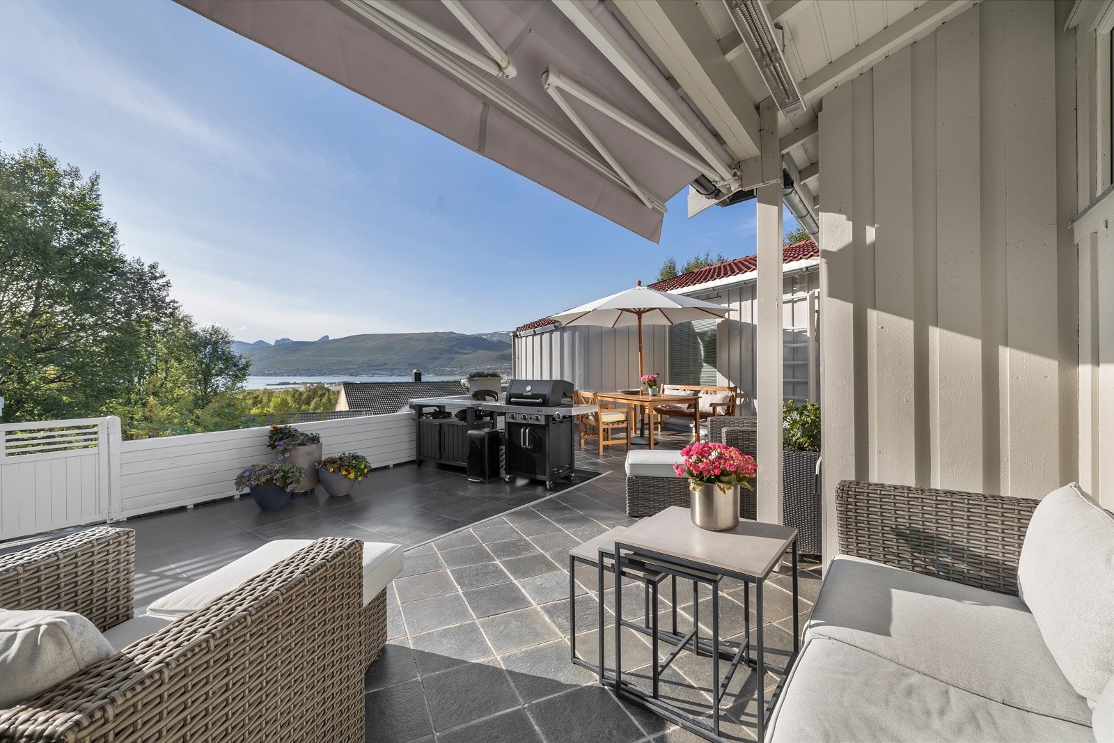 Stor veranda med plass til flere sittegrupper og utekjøkken Galleribilde