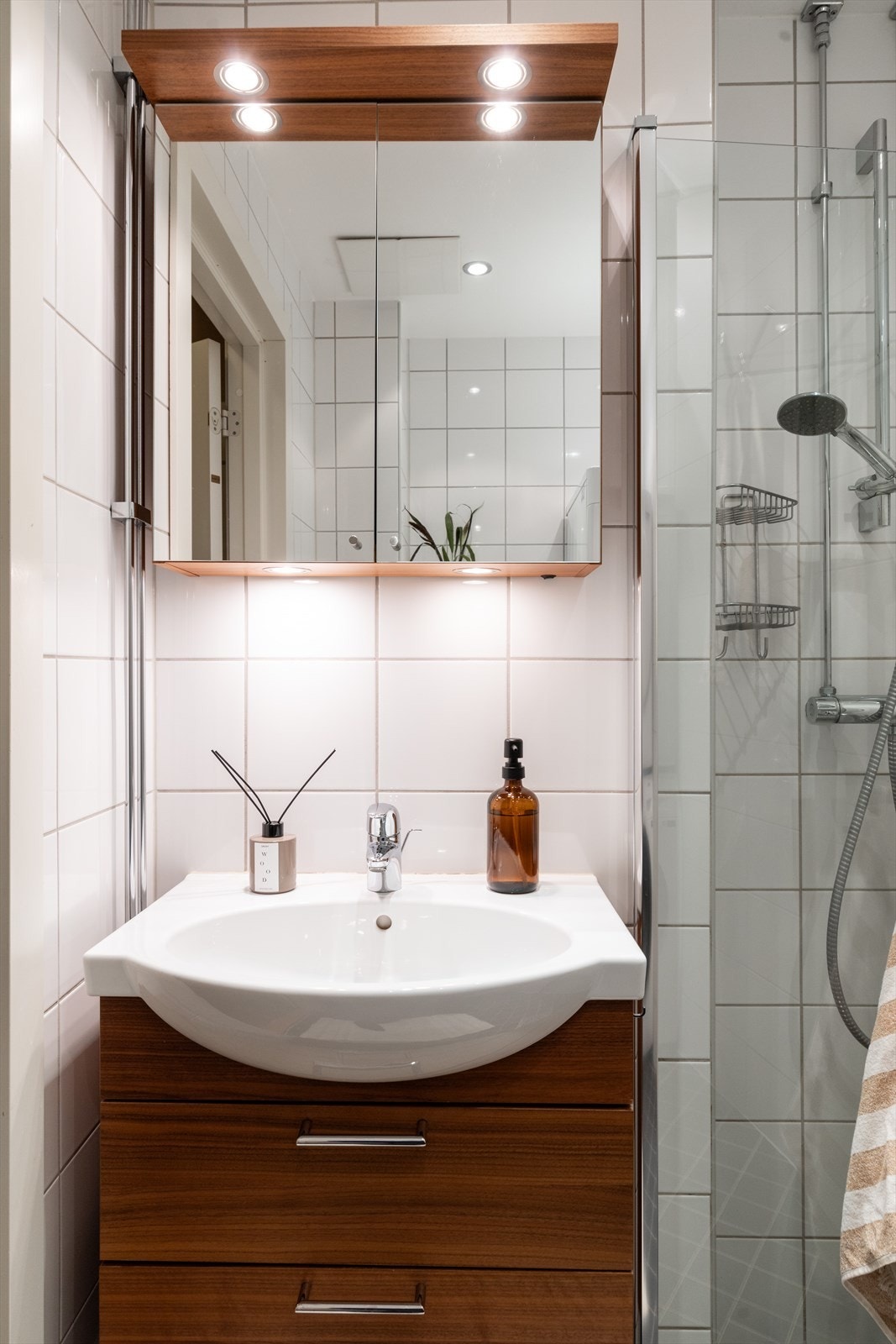 Badet er innredet med vegghengt klosett, servant med innredning, speilskap og dusjhjørne med svingbare glassdører. Galleribilde