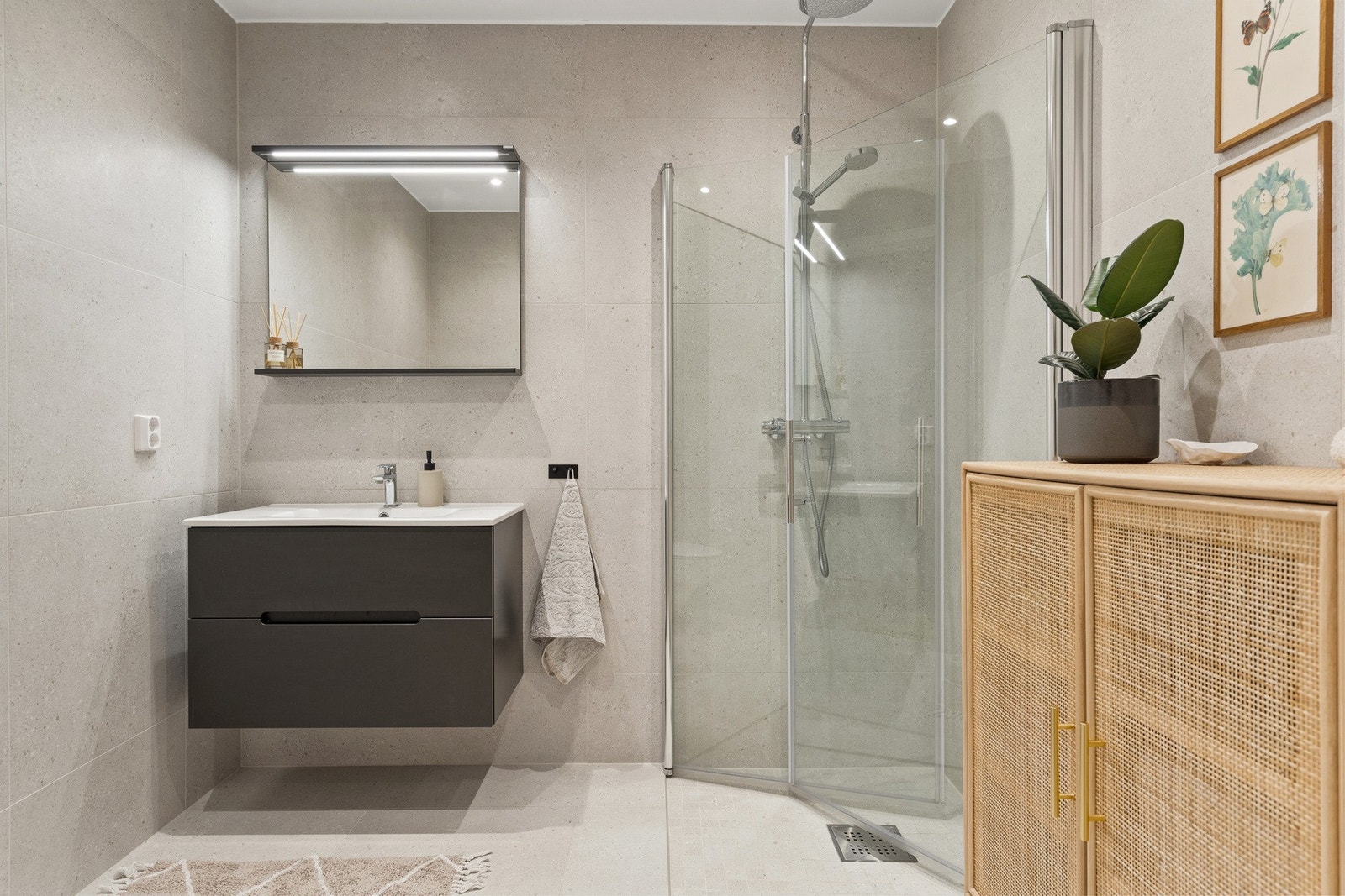 Badet er moderne og funksjonelt med flislagte overflater, vegghengt toalett, nedfelt servant og dusjhjørne. Galleribilde