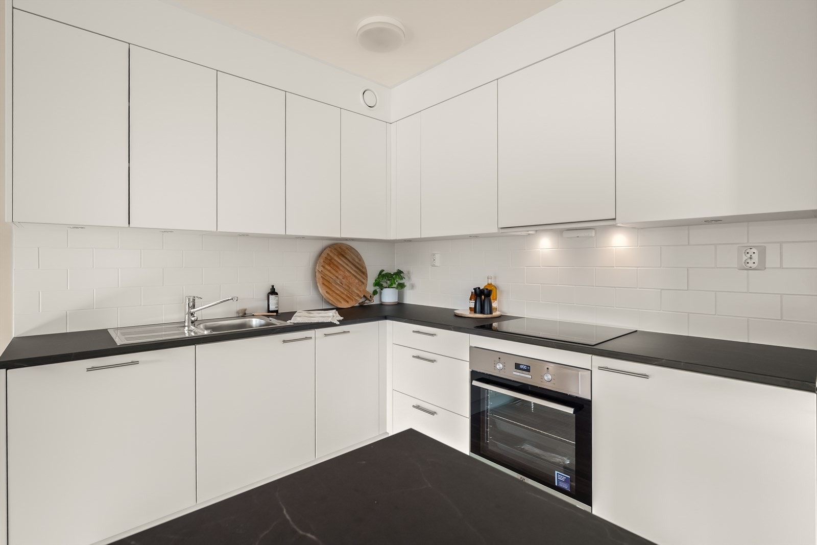 Mellom benkeplate og overskap er det fliser, og overskapene har integrert belysning. Galleribilde