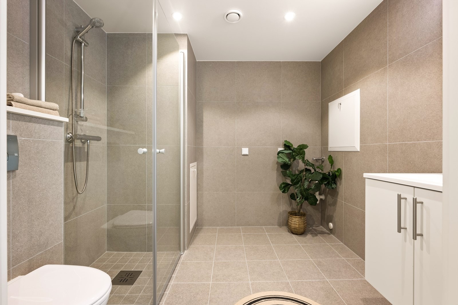 Vegghengt wc, dusjhjørne, opplegg til vask og tørk, samt servant i innredningen. Galleribilde