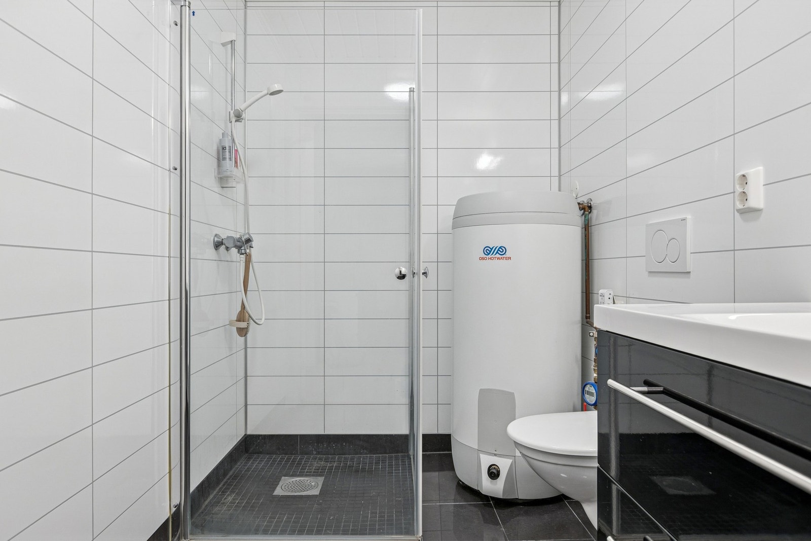 Badet i første etasje er moderne utstyrt med flislagte gulv, gulvvarme, dusjhjørne med innfellbare dører, servantskap og bereder. Galleribilde