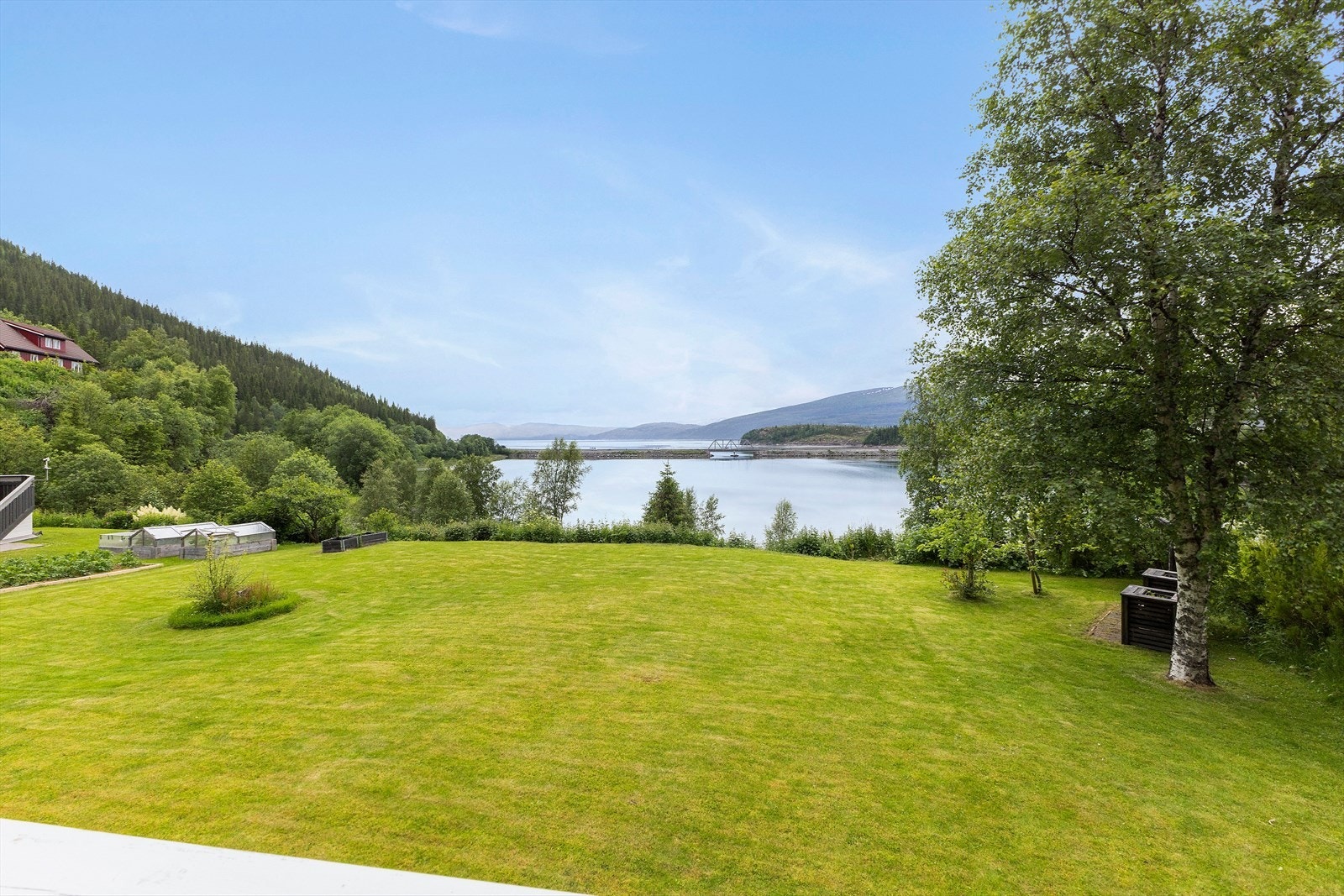 Hagen har en stor åpen gressplen - perfekt som familiens lekeområde. Rikelig av plass for den som ønsker å dyrke og drive med egne grønnnsakskasser. Til høyre på tomten finner du epletrær. Galleribilde