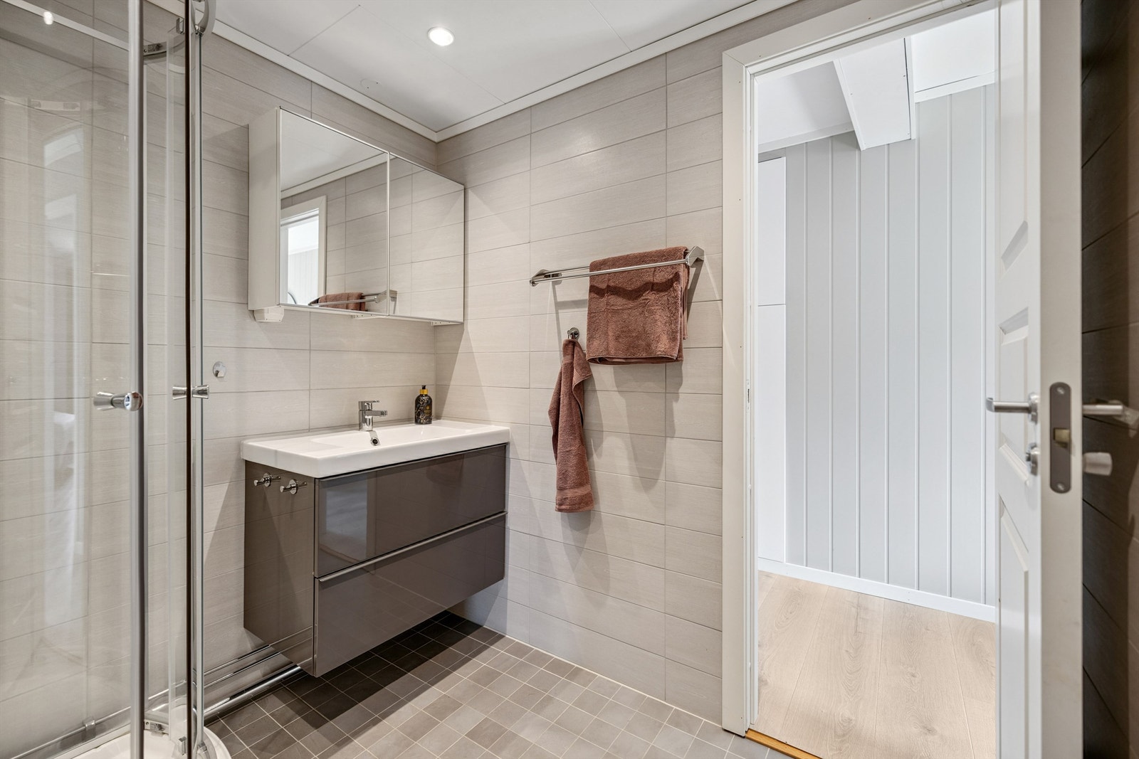 Rommet har elektrisk gulvvarme, servant i innredning, og et dusjkabinett fra 2024. Det er også opplegg for vaskemaskin. Galleribilde