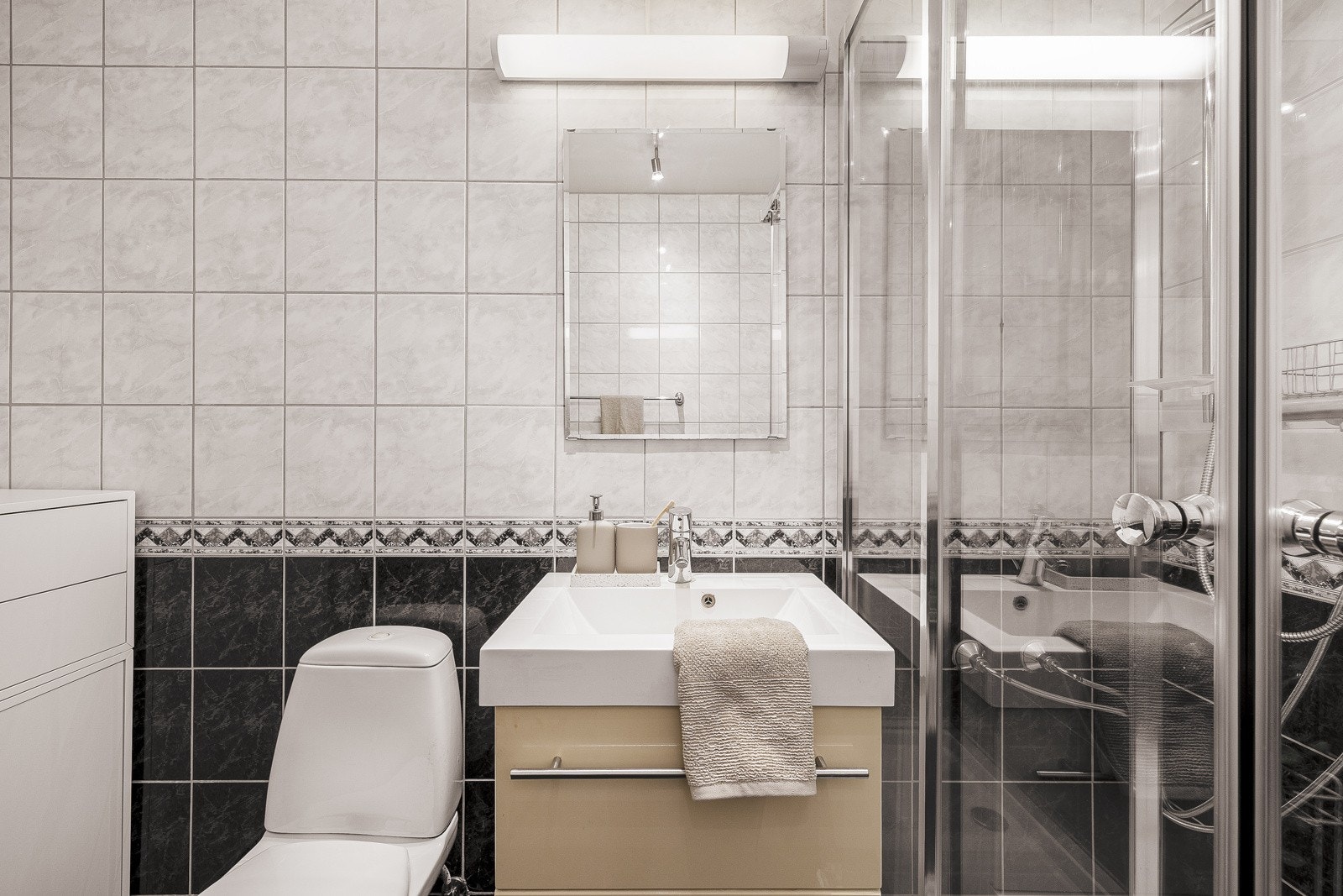 Badet er innredet med toalett, vask med underskap, dusjkabinett og lys over speil. Galleribilde