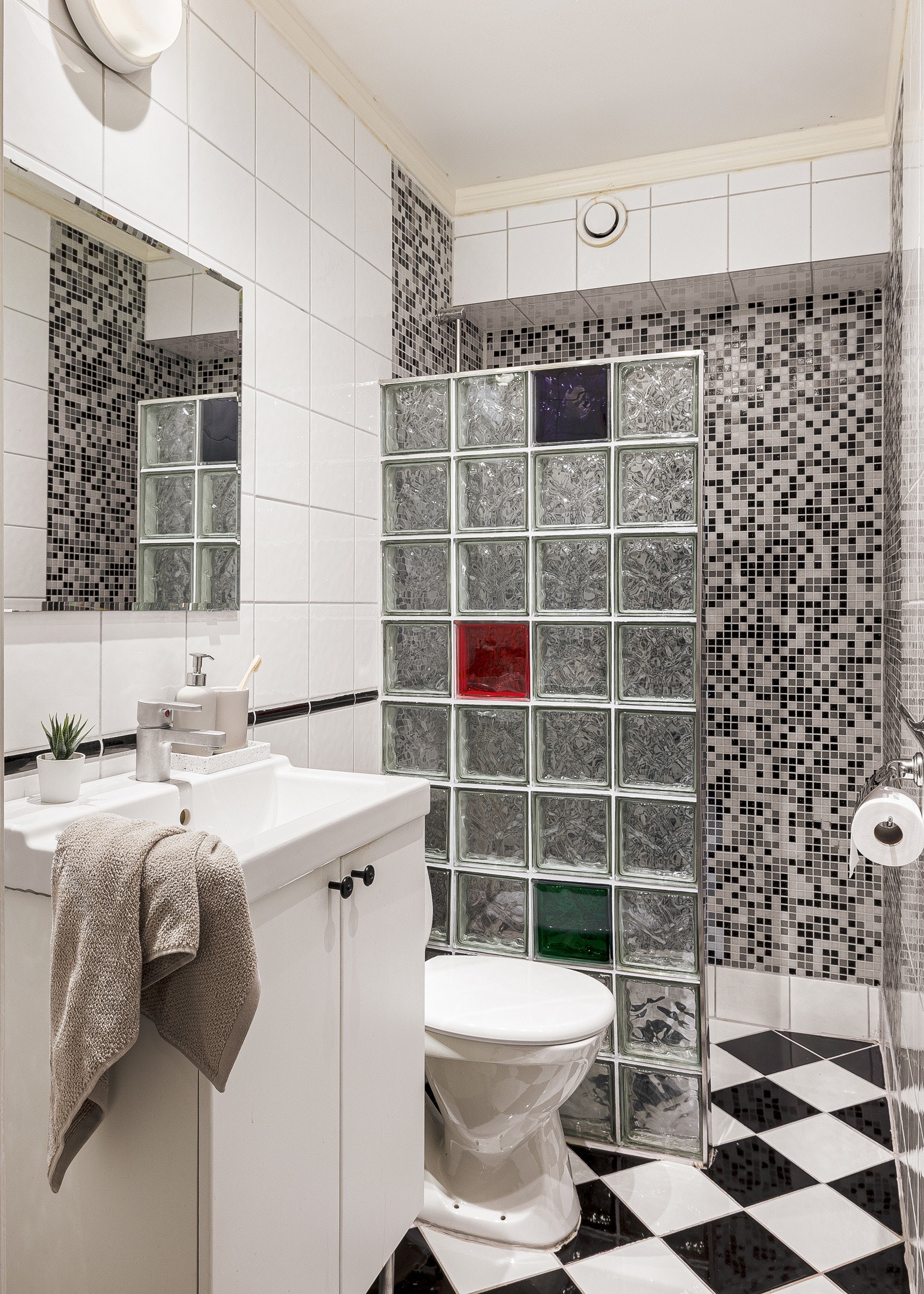 Bad på 2,6 kvm med fliser på gulv/ vegger og malt betong i taket. Badet er innredet med toalett, vask med underskap, lys over speil og dusj. Galleribilde