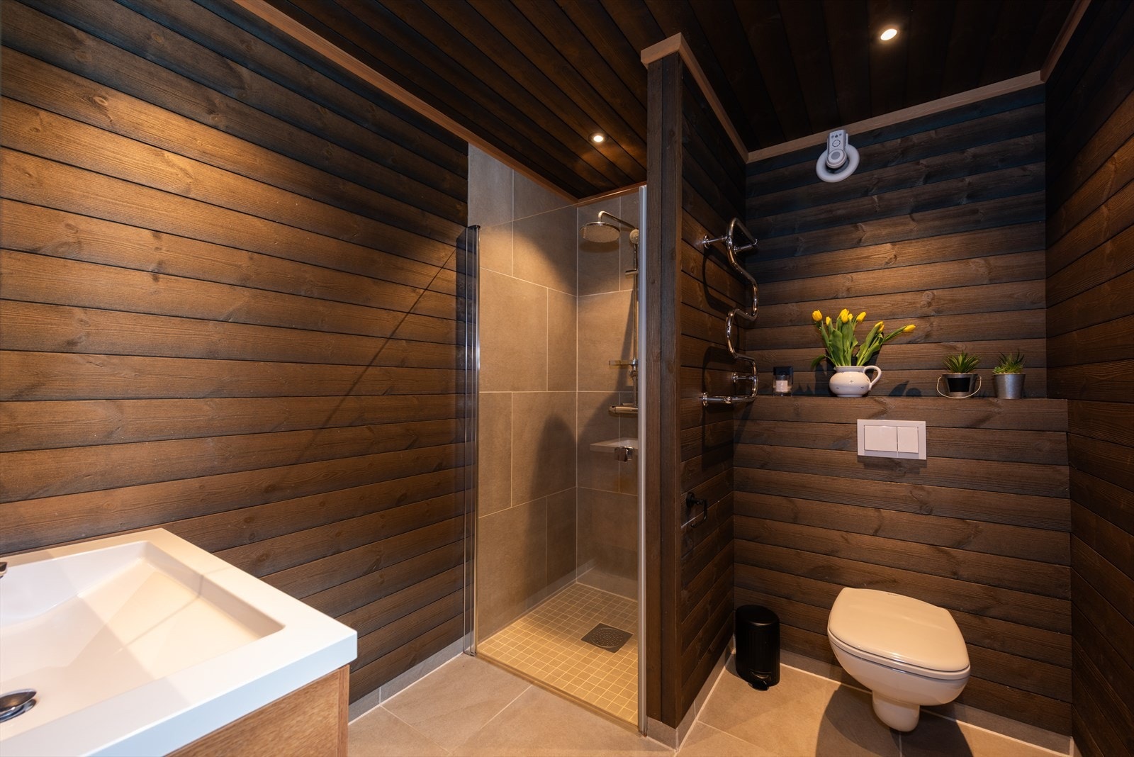 Bad med flislagt gulv og vegg i dusjnisje, ellers panel på vegger. Galleribilde