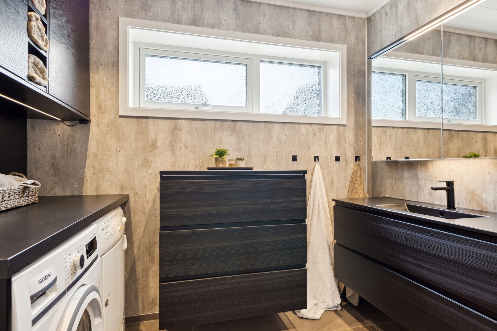 Innredning med nedfelt servant, veggmontert toalett, dusjhjørne og opplegg for vaskemaskin. Galleribilde