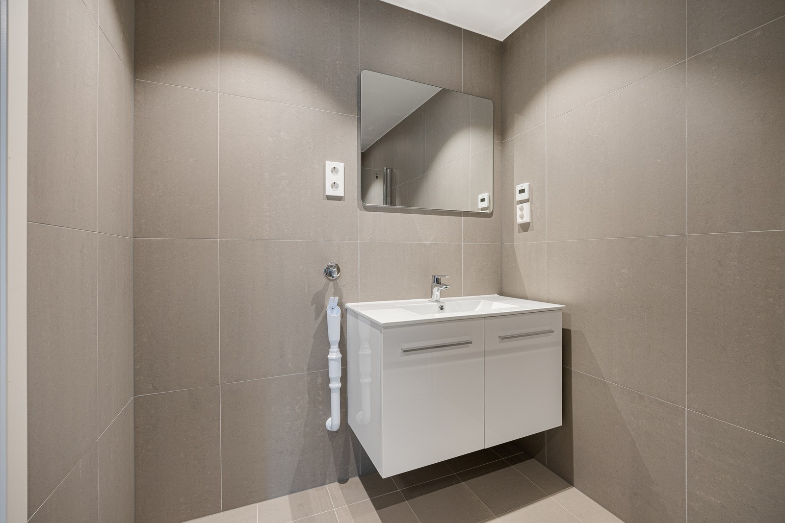 Innredningen har heldekkende servant over hvit skapseksjon, samt speil i overkant. Galleribilde