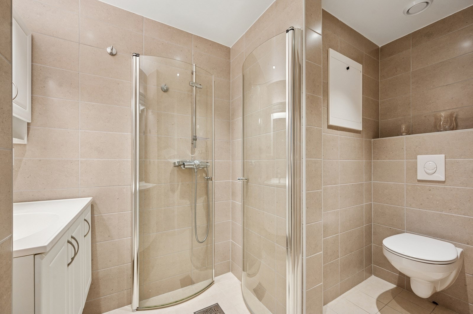 Badet er utstyrt med dusjhjørne, vegghengt tolaett og en lys baderomsinnredning. Galleribilde