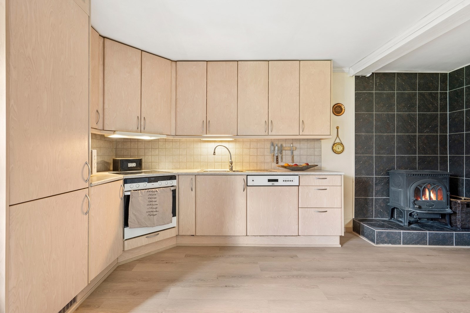 Kjøkkeninnredningen har lyse slette fronter og en benkeplate av laminat med nedfelt oppvaskkumi stål med ett-greps blandebatteri. Galleribilde