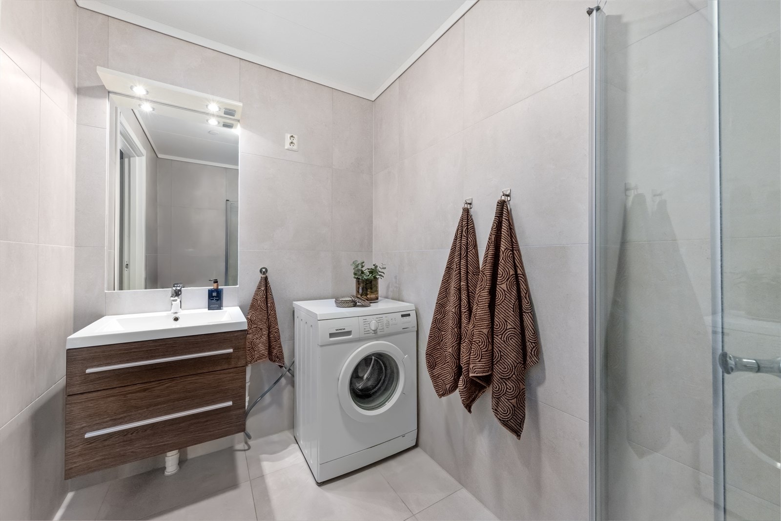 Rommet er utstyrt med innredning med nedfelt servant, toalett, dusjhjørne med glassvegger og opplegg for vaskemaskin. Galleribilde