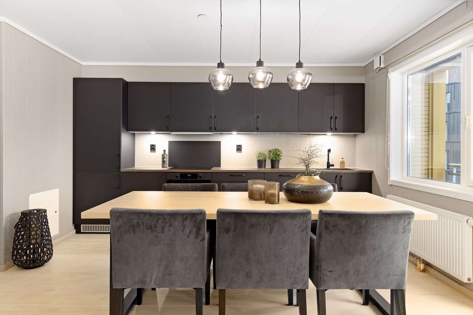 Kjøkkenet har en stilren, sort innredning med glatte fronter og en praktisk benkeplate i laminat som gir både funksjonalitet og et moderne uttrykk. Galleribilde