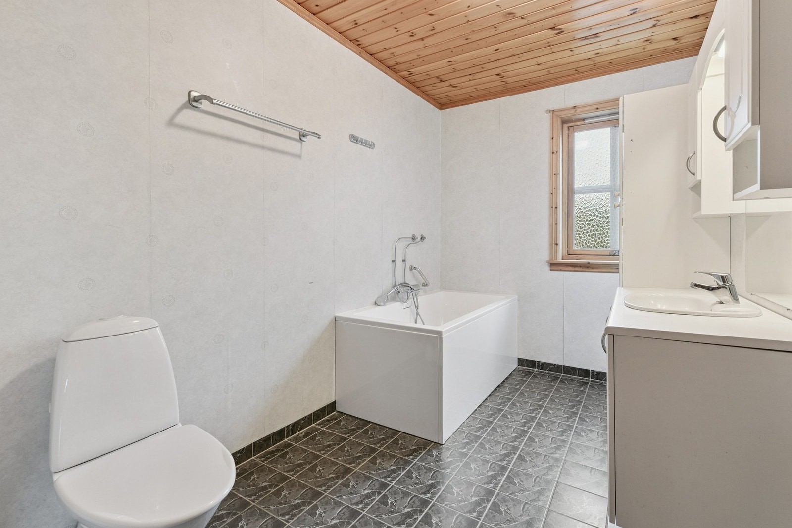 Bad i hovedetasjen med baderomsinnredning, badekar og toalett. Galleribilde