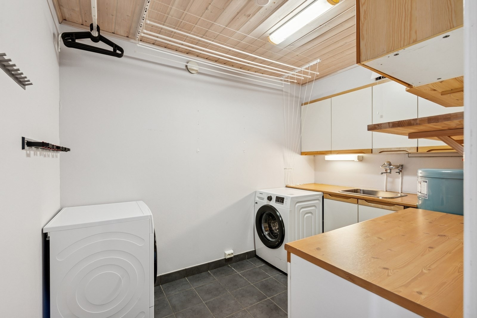 Rommet har plass med opplegg til vaskemaskin, og er innredet med oppbevaringsmuligheter samt benkeplass med nedfelt vaskekum Galleribilde