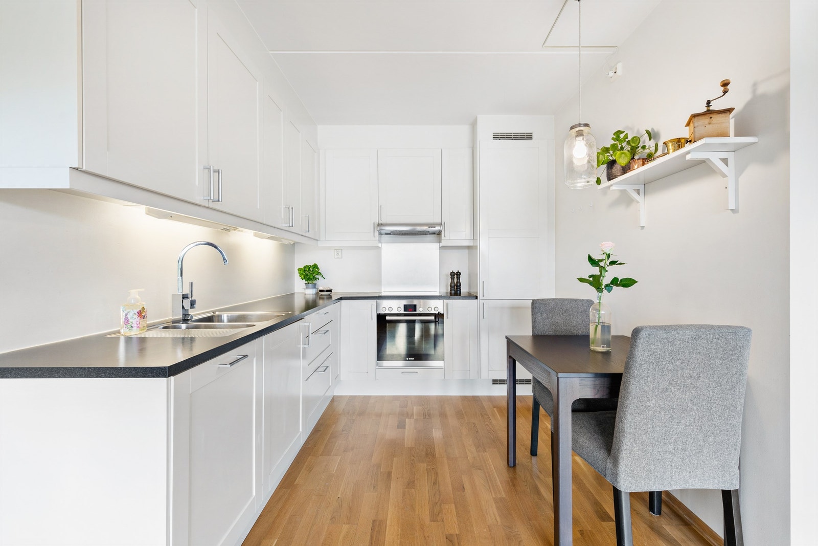 Kjøkken med åpen løsning mot stue. Plass til mindre kjøkkenbord med stoler. Kjøkkeninnredning fra byggeår. Profilerte fronter. Benkeplater av laminat. Nedfelt oppvaskkum med ett-greps armatur. Ventilator mellom overskap. Varmtvann fra felles varmesentral. Galleribilde