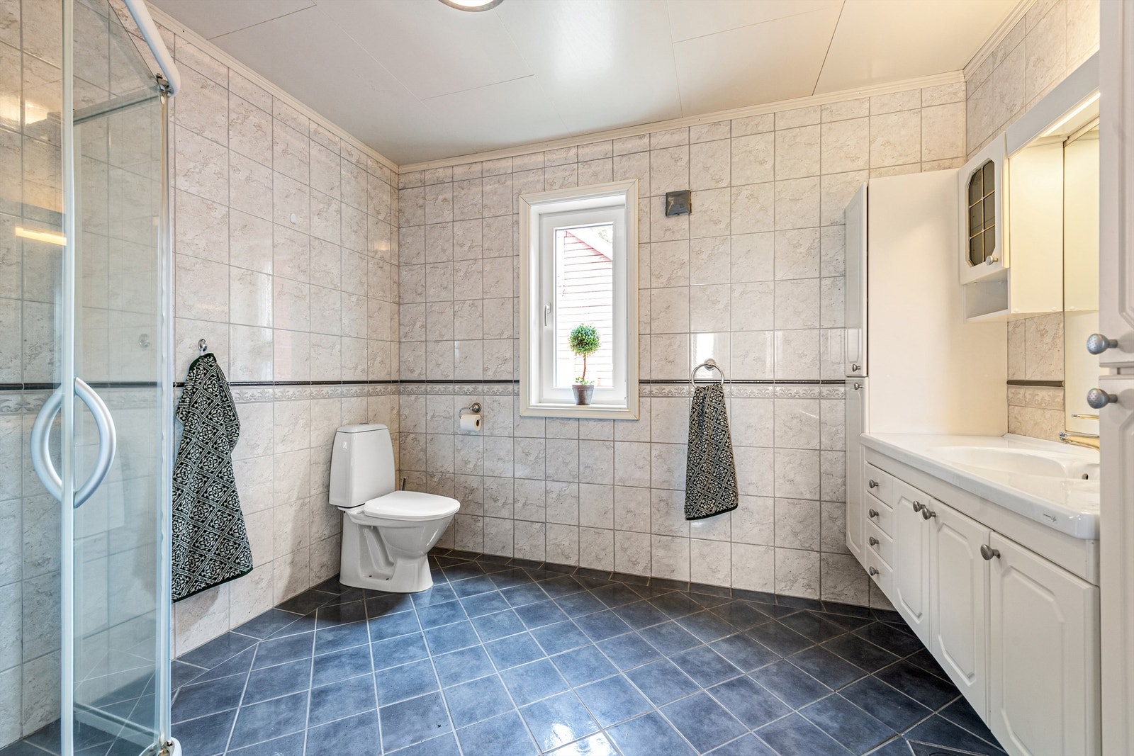 Flislagt bad med romslig innredning. Dusjhjørne og toalett. Galleribilde