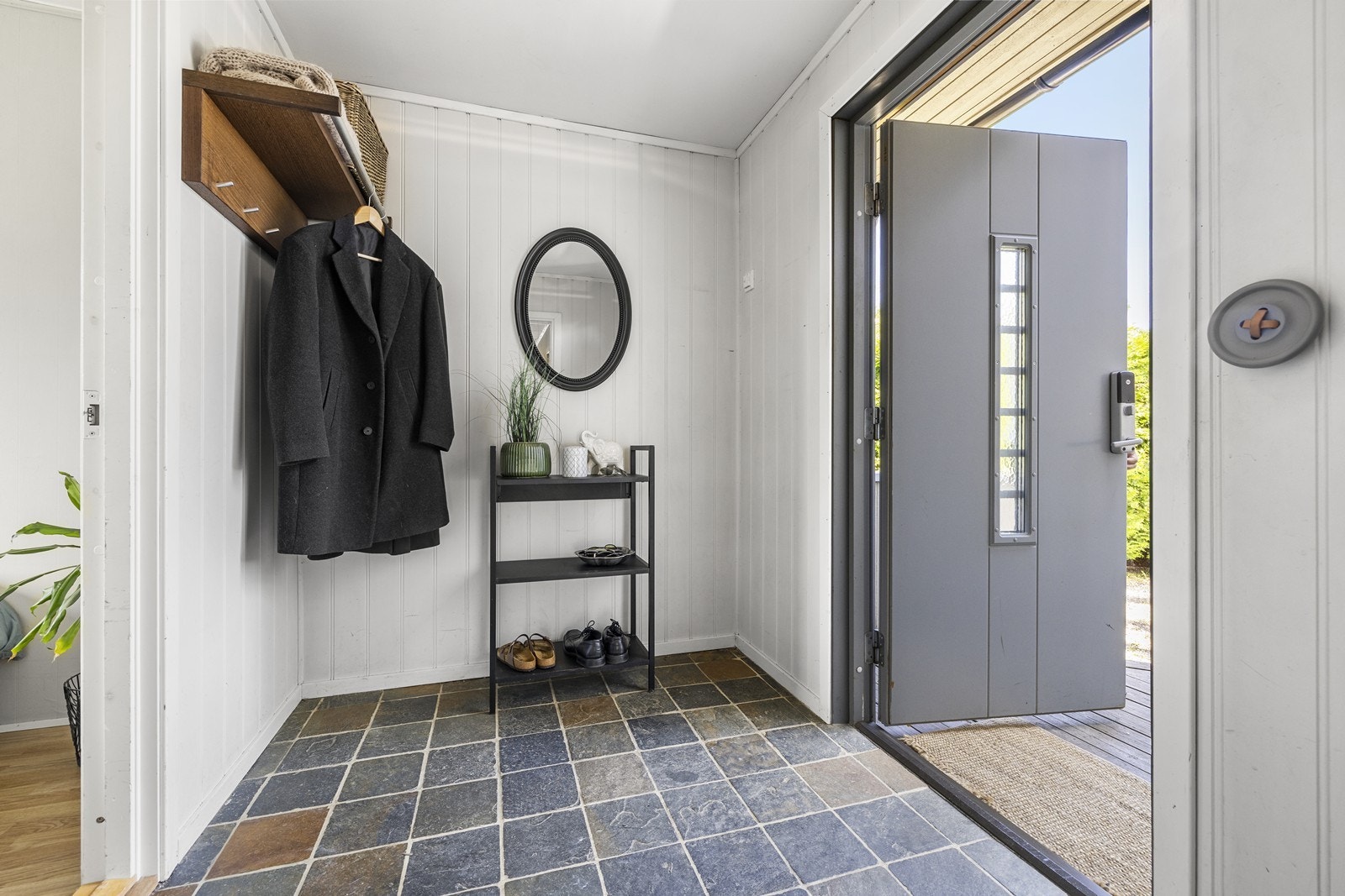 Velkommen inn. Gangen har flislagt gulv med gulvvarme og en praktisk ytterdør med kodelås. Galleribilde