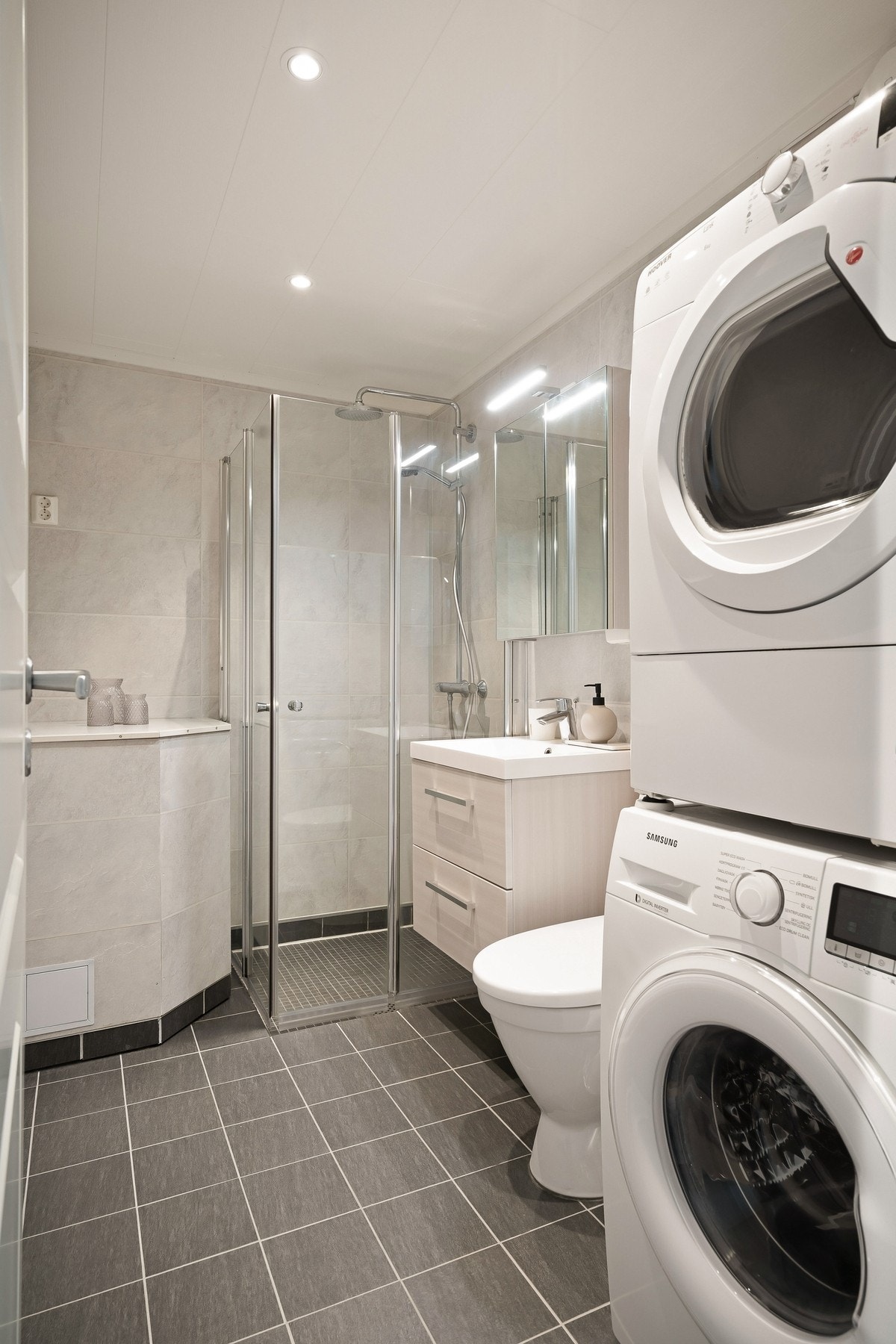 Flislagt bad med dusjhjørne, toalett, nedfelt servant og opplegg for vaskemaskin. Galleribilde