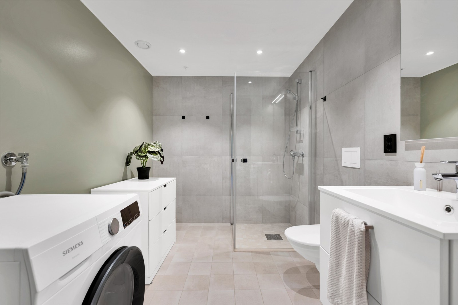 Badet er innredet med plassbesparende og innfellbare dusjvegger i glass, veggmontert WC, kran/avløp for vaskemaskin samt servant på underskap og speil. Galleribilde