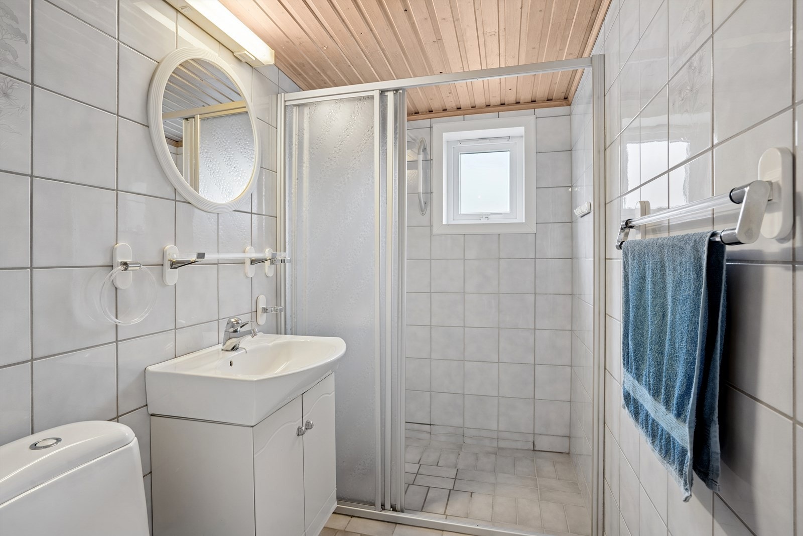 Badet er fra tidlig 1990-tall og har en eldre standard. Rommet er innredet med nedfelt servant, gulvmontert toalett og dusjnisje. Galleribilde