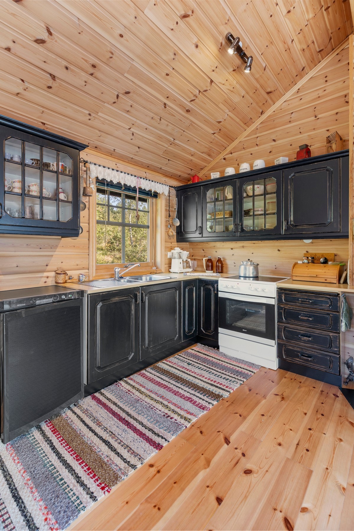 Innredningen inneholder laminat benkeplate, oppvaskkum, kjøleskap og komfyr. Galleribilde