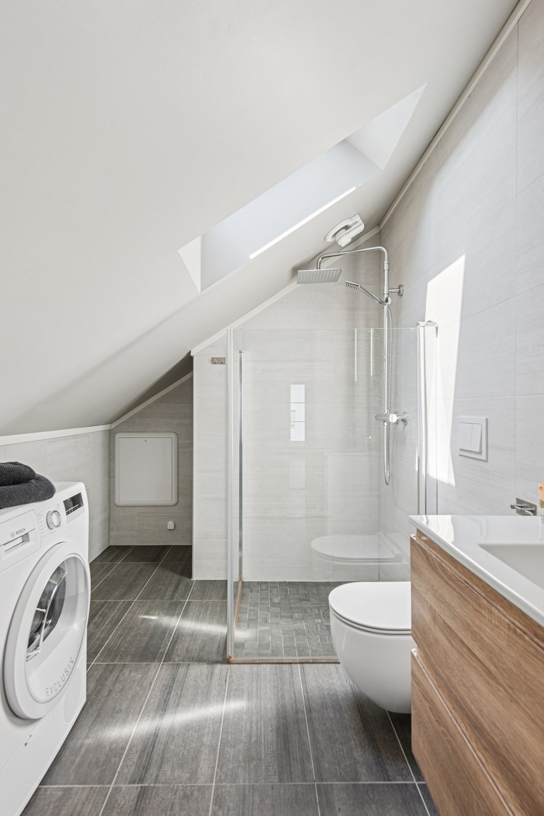 Baderommet holder god standard med gulvvarme, fliser, vegghengt toalett og dusjløsning med glassvegger, samt opplegg for vaskemaskin. Galleribilde
