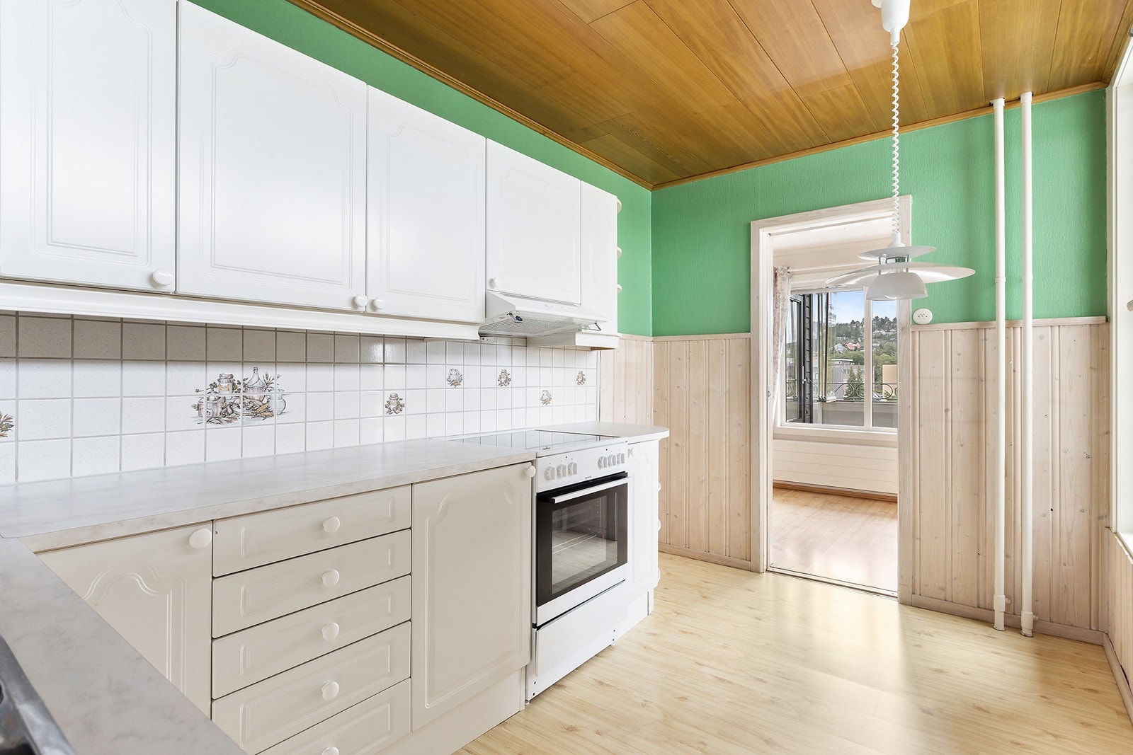 Kjøkkeninnredning med 1-speils fabrikklakkerte fronter, laminat benkeplate m/fliser over, dobbel oppvaskkum og ventilator. Galleribilde