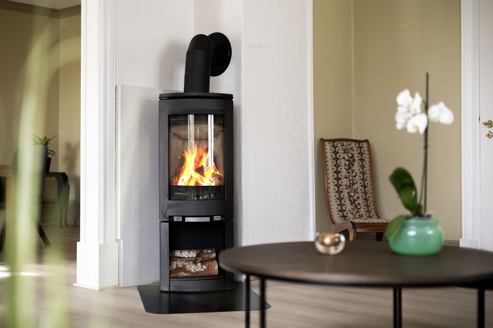 Moderne vedovn med glassfront, plassert i et hjørne, gir varme og koselig atmosfære. Galleribilde