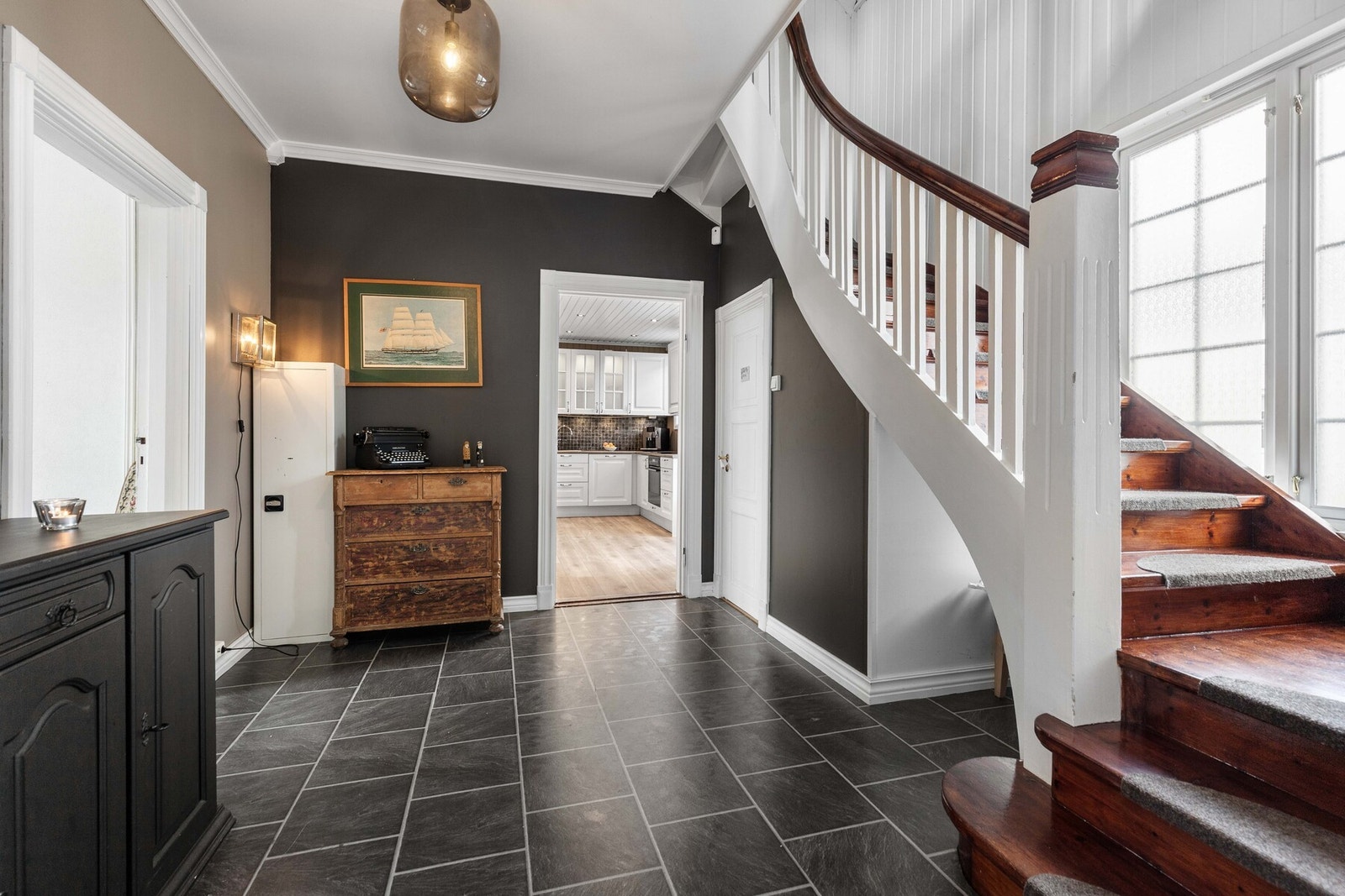 Innenfor entreen er det en romslig hall med mørke gulvfliser og adkomst til kjøkken og stue. Galleribilde