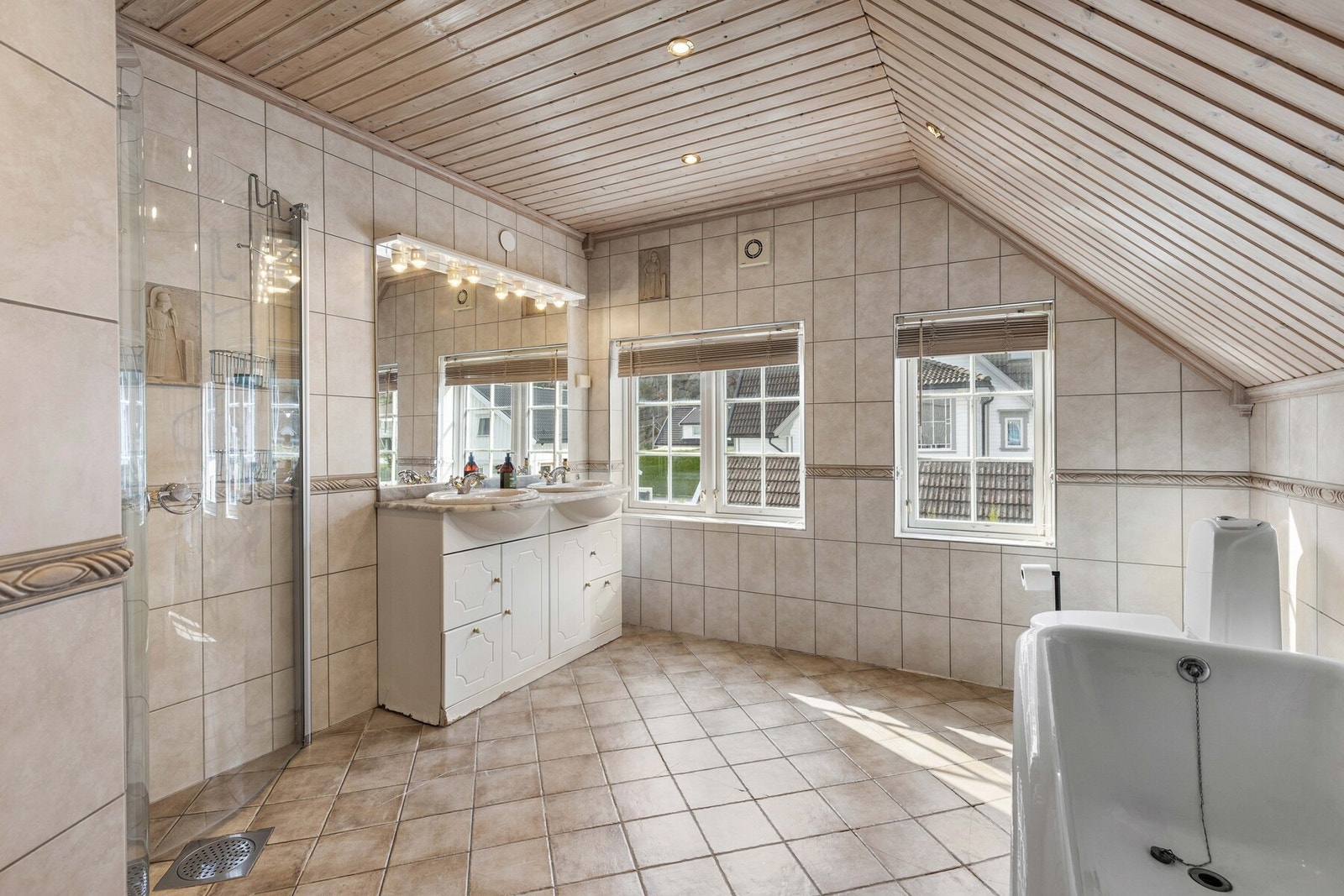 Lyst bad med fliser, dobbel vask, dusj og badekar. Galleribilde