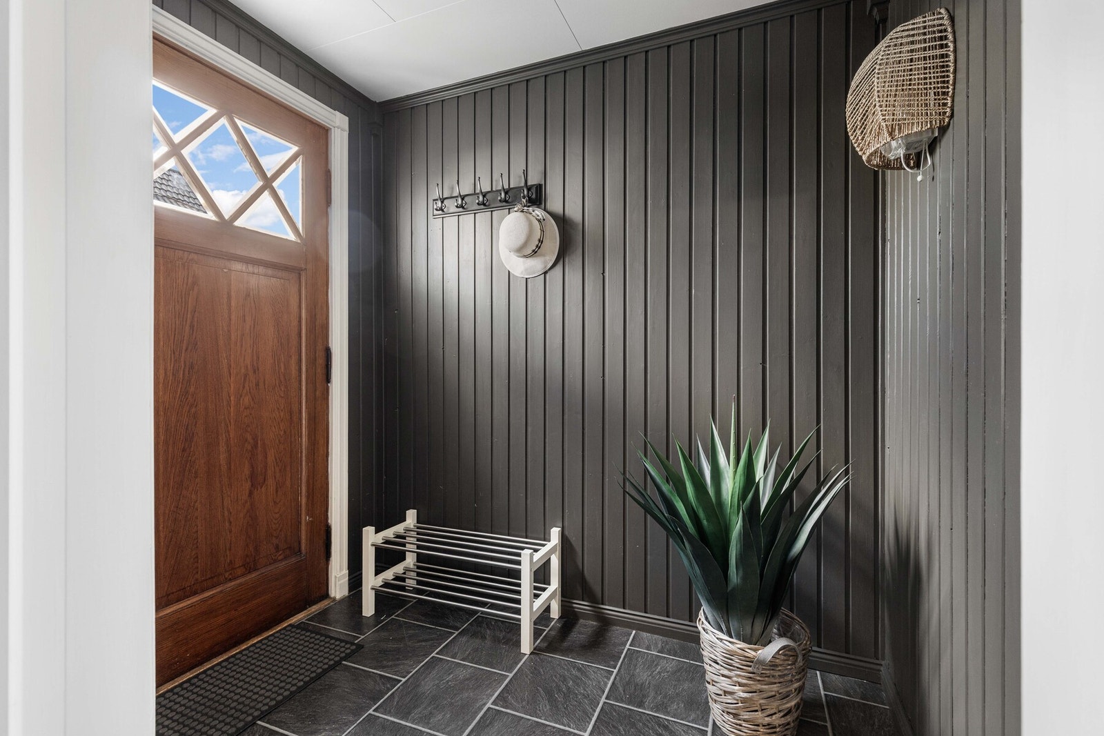 Entreen har mørke gulvfliser og åpen garderobeløsning Galleribilde