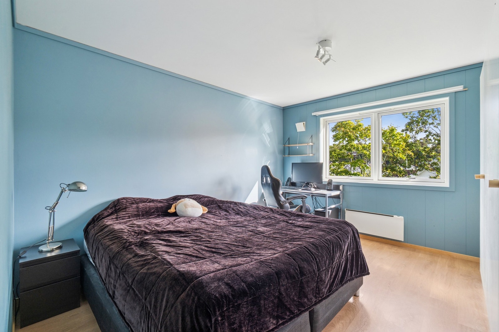 Romslig soverom malt i en fin blåtone. Rommet har garderobeskap. Galleribilde