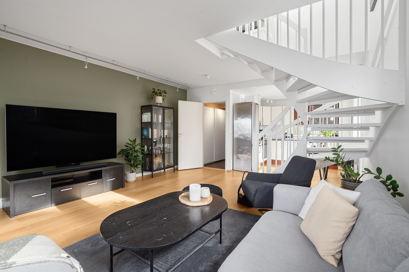 Den åpne løsningen mellom stue og kjøkken skaper en naturlig og innbydende atmosfære, med plass til både sofagruppe, TV-seksjon og spisebord. Galleribilde