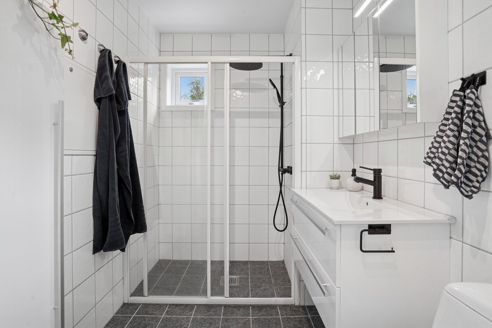 Badet er utstyrt med servantinnredning, toalett og dusjhjørne med glassdør. Her har man også opplegg for vaskemaskin og plass til tørketrommel. Galleribilde