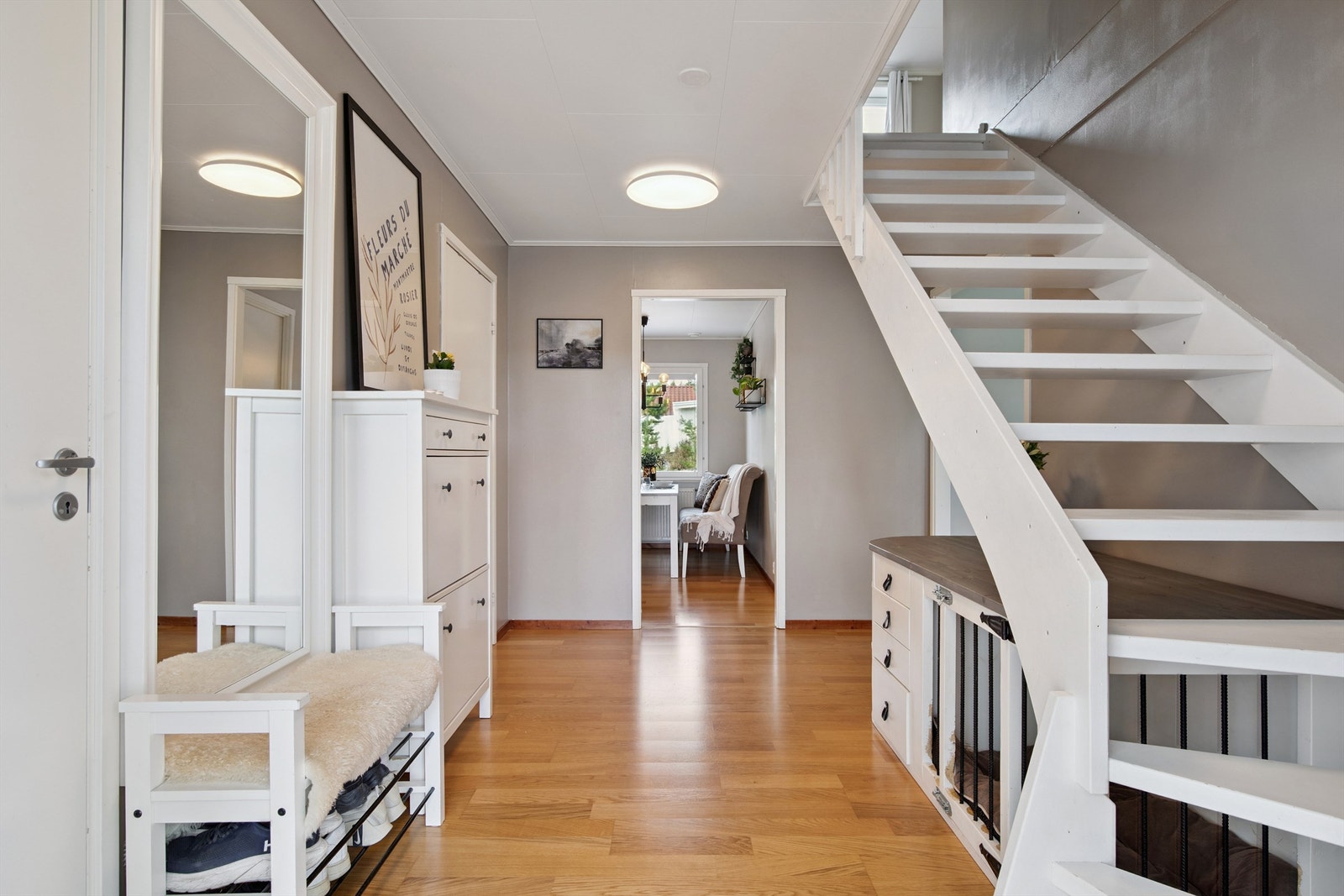 Velkommen inn! Entré med laminatgulv og lyse overflater og en malt, åpen tretrapp som binder etasjene sammen. Galleribilde