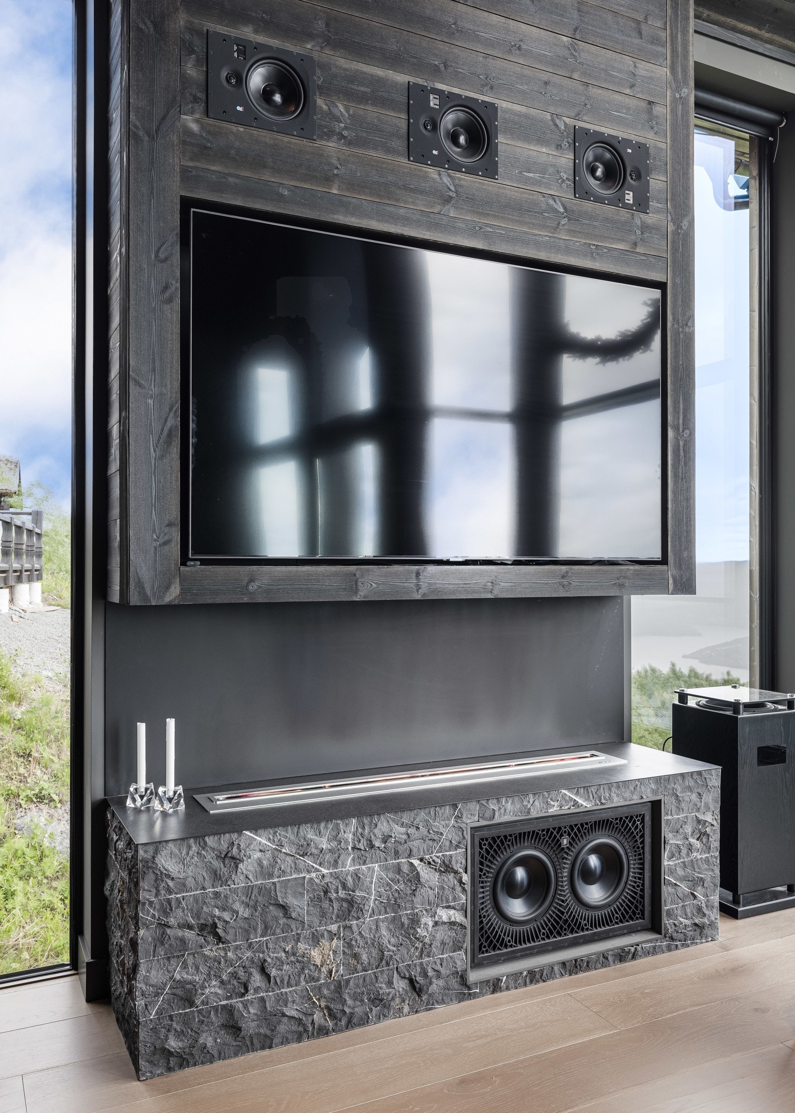 Tilpassede TV-benker med integrert lydsystem og bioetanolpeiser skaper en koselig atmosfære.