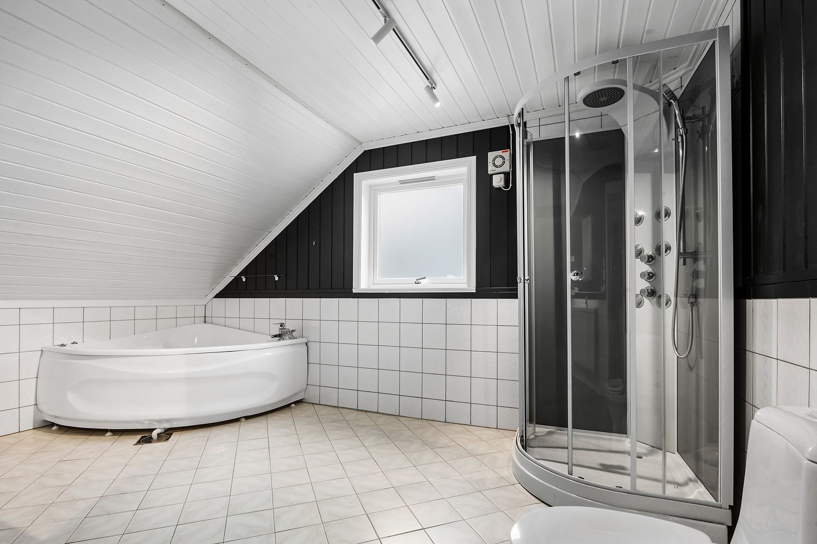 Romsleg bad med flislagt golv med varmekablar er innreiia med både hjørnebadekar og dusj Galleribilde