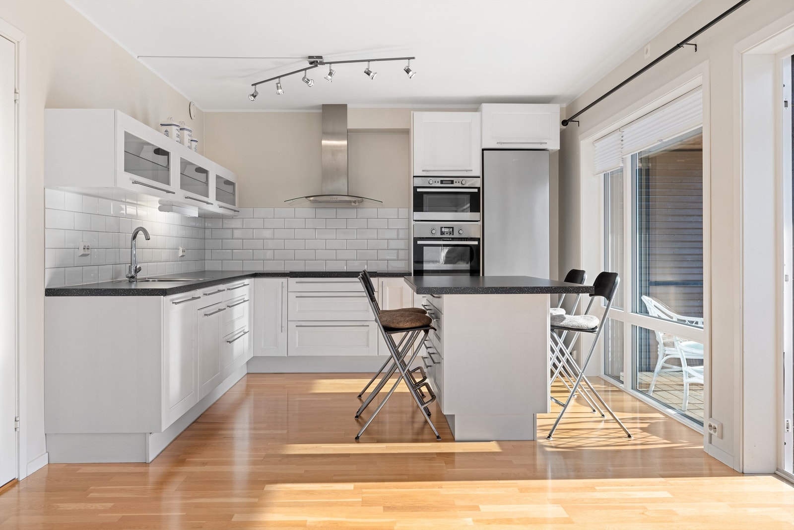 Lys kjøkkenløsning med god benkeplass og stilrene hvite flater Galleribilde