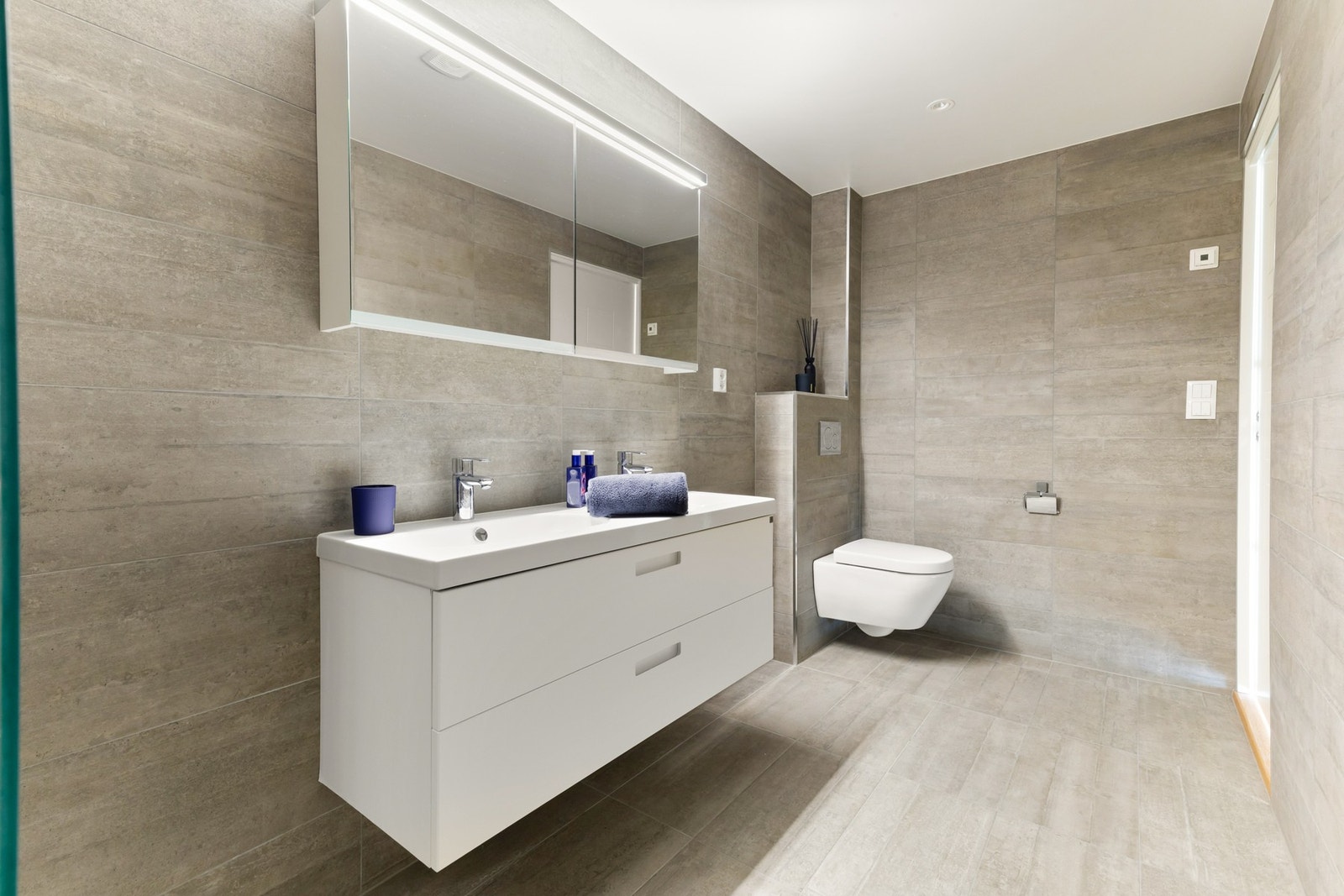 Baderom med dobbel servant, stor dusjnisje og rikelig med oppbevaring i speil og innredning. Galleribilde