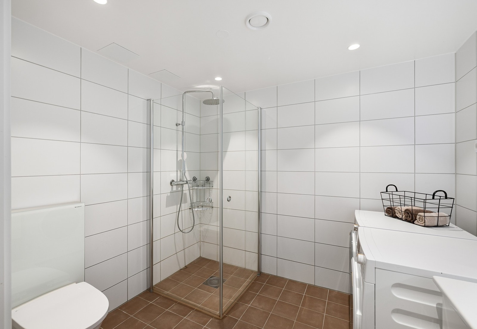 Stilrent bad med delikate, store hvite fliser på vegg kombinert med varme gulvfliser skaper et rent og behagelig uttrykk. Galleribilde