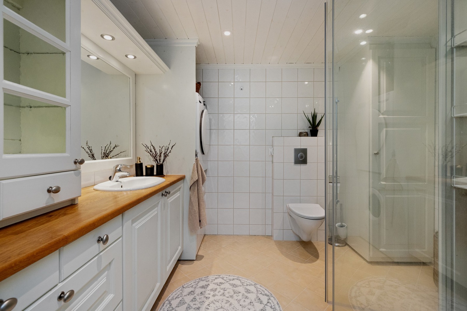 Badet har delikate detaljer. Flislagte overflater på vegger og gulv. Flott innredning i heltre og profilertte fronter i malt utførelse. Godt med skapplass Galleribilde