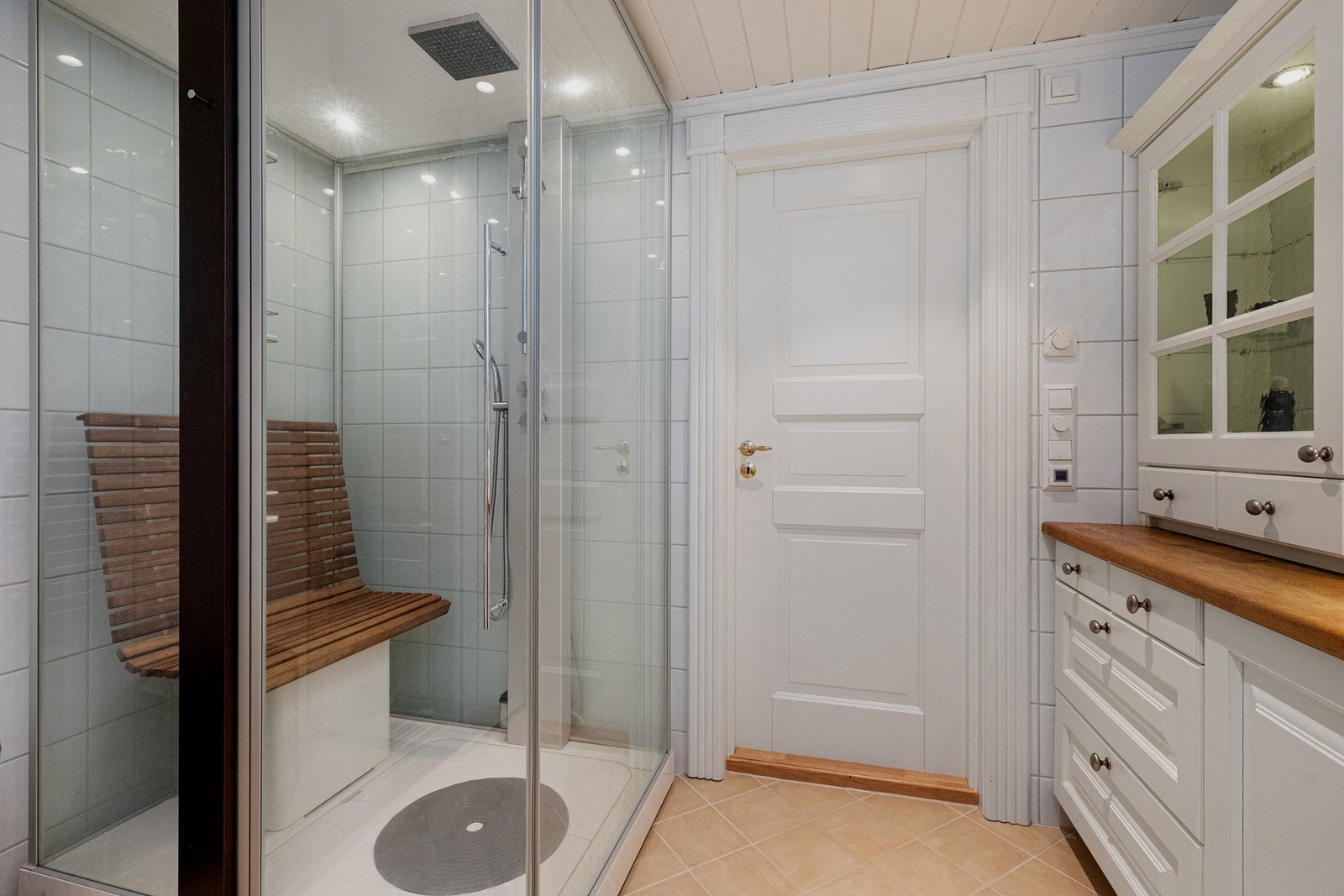 Romslig dusjnisje med glassdører - en sittebenk er plassert i dusjsonen Galleribilde