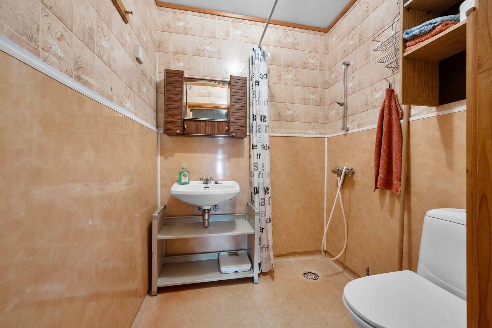 Badet i underetasjen er fra byggeår og er innredet med dusj med forheng, gulvmontert toalett og enkel servant. Galleribilde