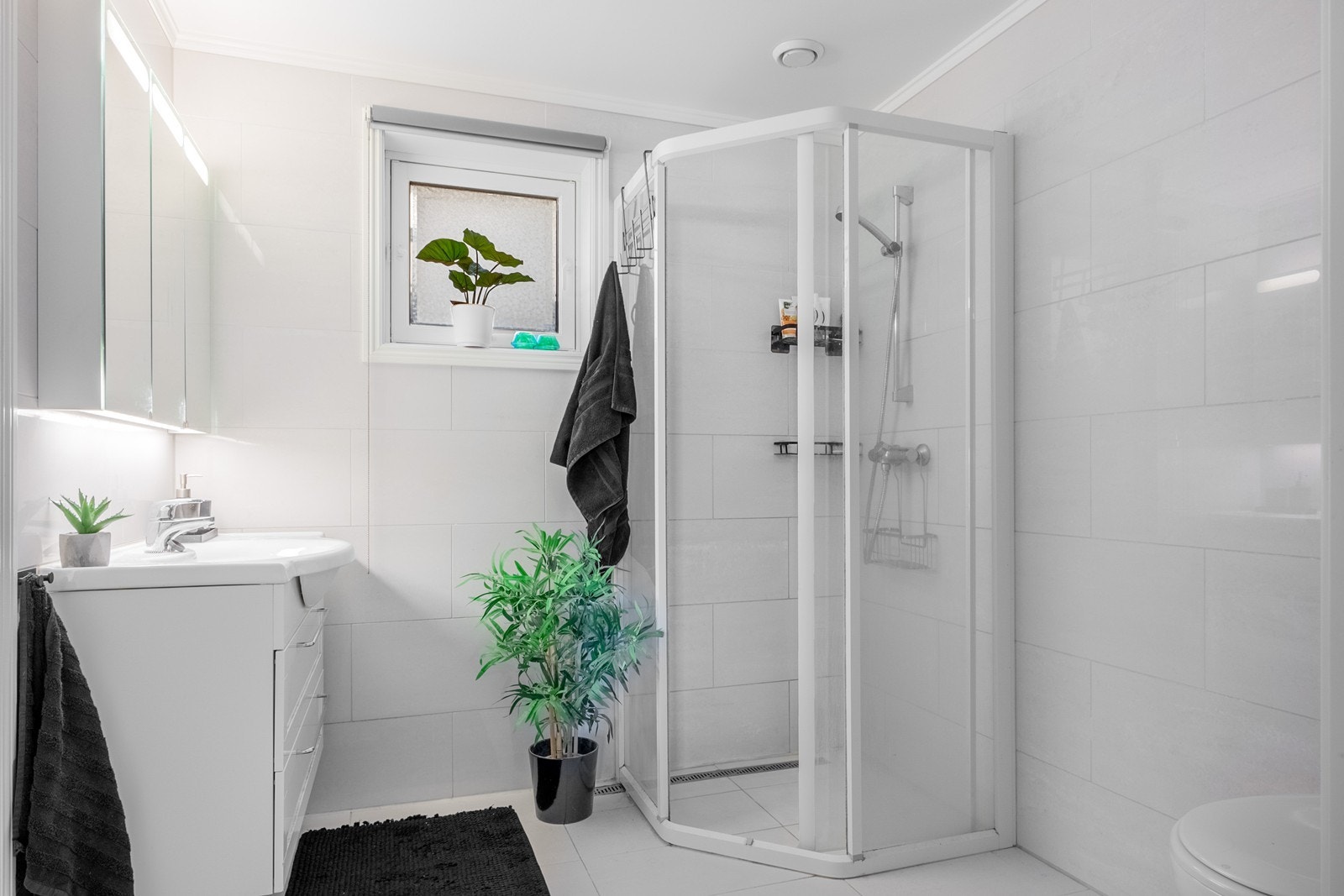 Badet fra byggeår er tidløst med lyse, flislagte overflater og vannbåren varme. Innredningen består av dusjhjørne med kabinettdører, veggfestet toalett og servant. Galleribilde