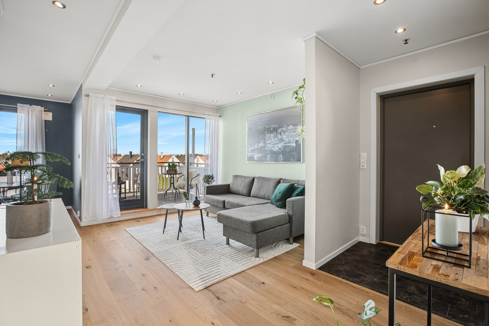 Legg merke til den smarte løsningen med veggen som skiller stuen mot entreen.
Videre inn ligger den nydelige, lyse stuen. Rommet har en praktisk planløsning med kjøkkenet tett tilknyttet. Galleribilde